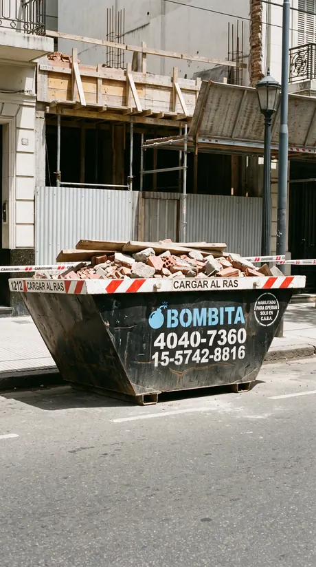 Volquete Bombita cargado y listo para el retiro frente a una obra con andamios